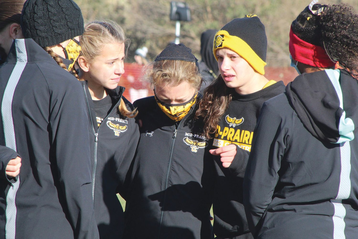 Members of Mid-Prairie’s girls cross country team huddle for an inspirational talk just before the start of the state championship race on Oct. 31.